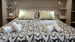 A bed with a heart-patterned bedspread, two striped pillows, and two rolled towels. - Tuscan Barn 15 min from Florence, Parking, Garden (Pian di Mugnone)