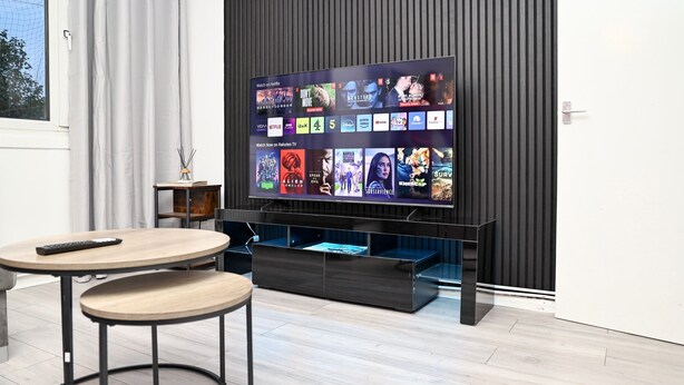 A modern living room with a flat-screen TV displaying various streaming services, a wooden coffee table, and a small side table with a remote control. - Kingston Duplex Apt Balcony, Parking & Wi-fi (Kingston Upon Thames)