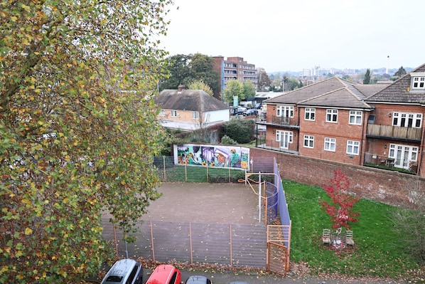 Un quartier résidentiel doté d’un terrain de sport clôturé, de bâtiments en briques et d’une fresque murale.