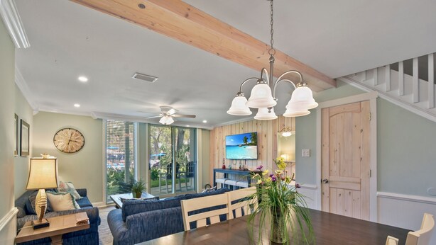 A dining area with a wooden table, blue sofas, and a ceiling fan. - Villa 332: 2  BR, 1.5  BA Condominium in Jekyll Island, Sleeps 6 (Jekyll Island)