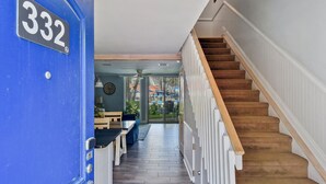 A hallway with a blue door labeled 332, a wooden staircase, and a view of an outdoor area with umbrellas. - Villa 332: 2  BR, 1.5  BA Condominium in Jekyll Island, Sleeps 6 (Jekyll Island)