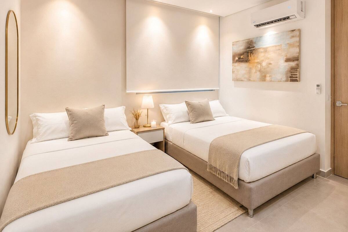 A hotel room with two beds, a wall-mounted air conditioner, and a painting.