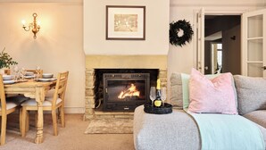 A cozy living room with a fireplace, a dining table set for four, and a comfortable seating area with a couch.