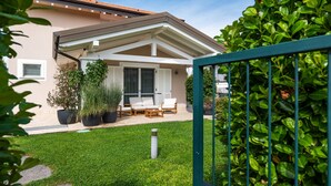 A house with a covered patio, a lawn, and a metal gate. - Green Lodge - Villa Tortora (Cressa)