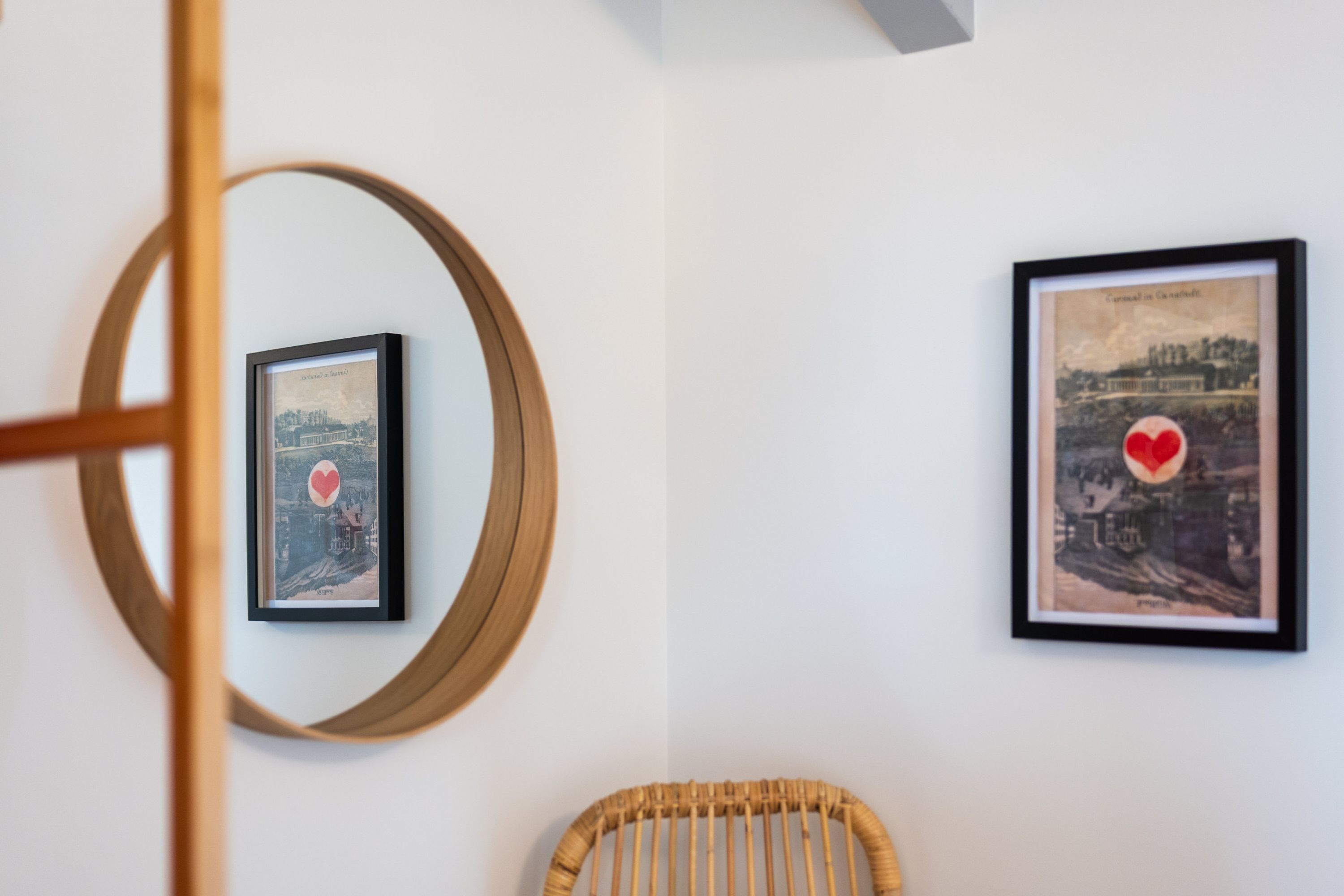 Two framed pictures on a wall, one with a heart and one with a cityscape.