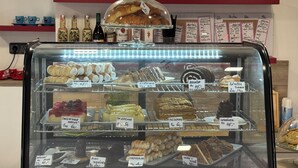 Ett skyltfönster för ett bageri med ett urval av olika bakverk och desserter.