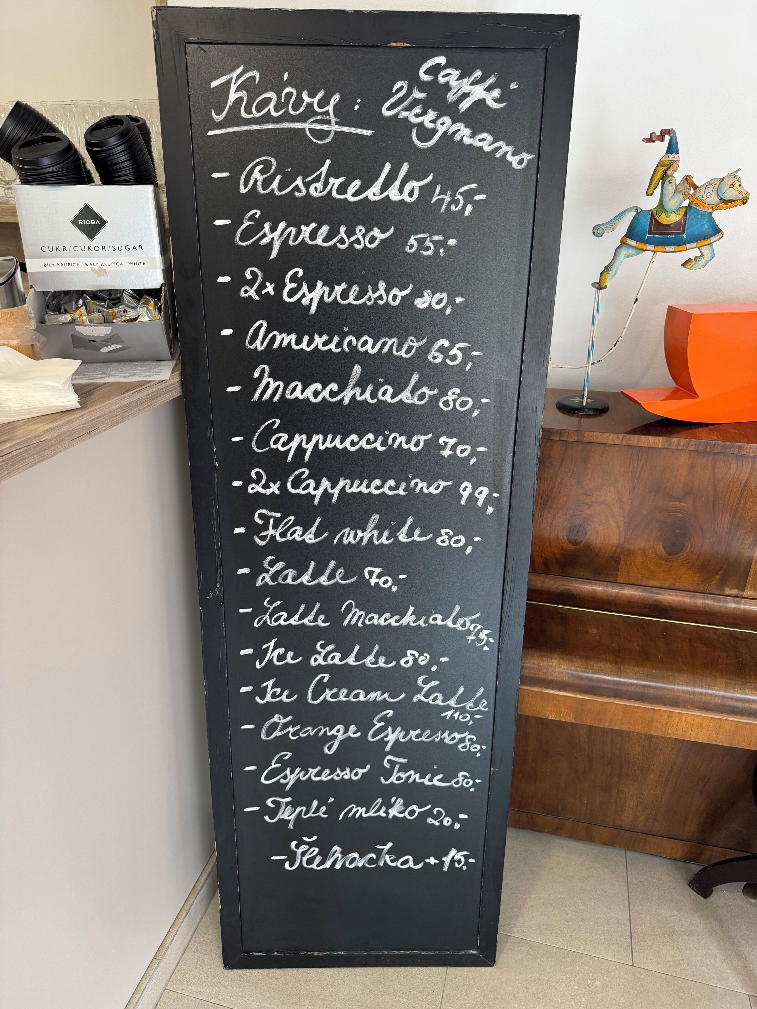 A chalkboard menu listing coffee and milk options with prices.