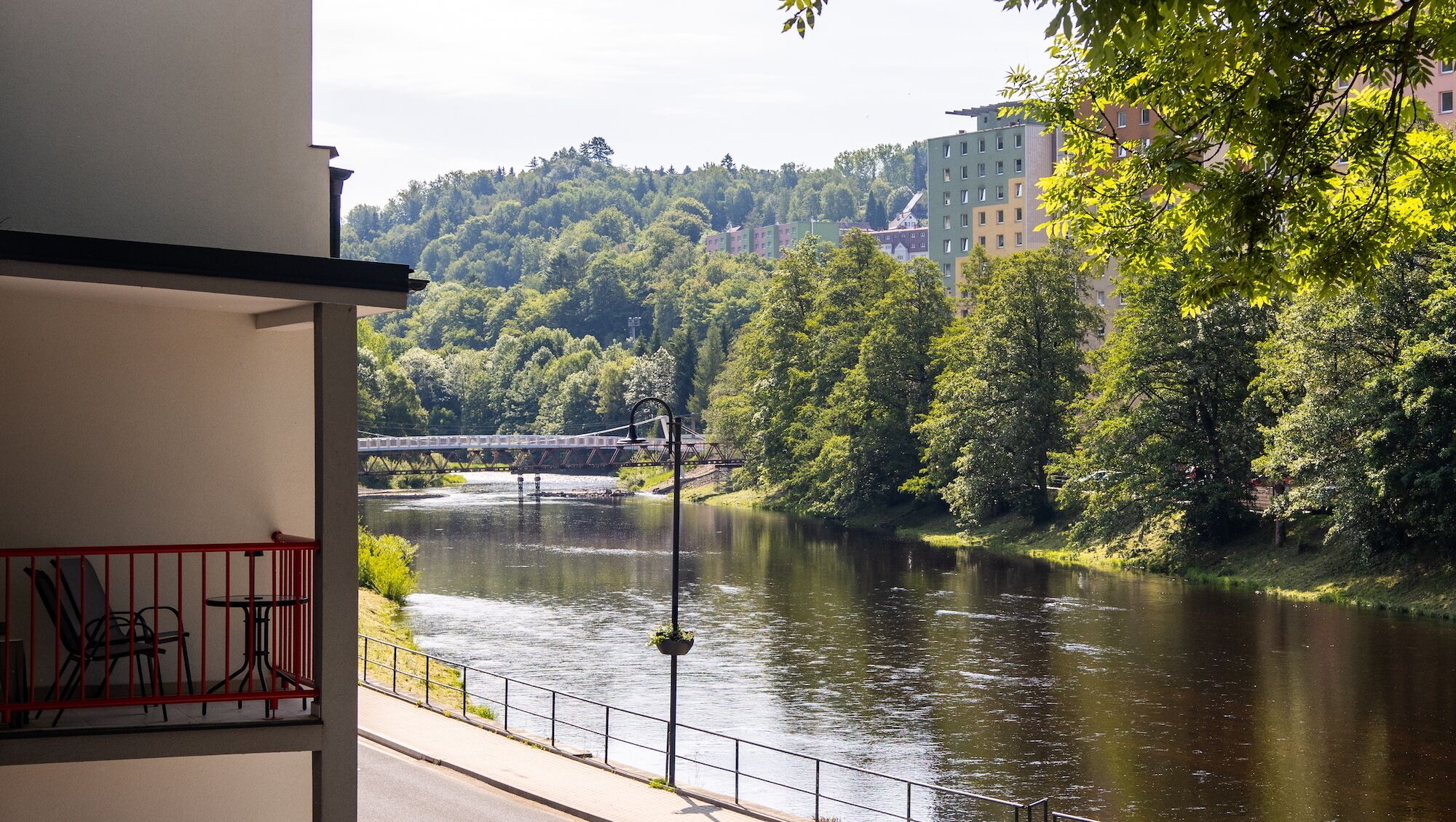 A view of a river with a bridge, surrounded by greenery and buildings.