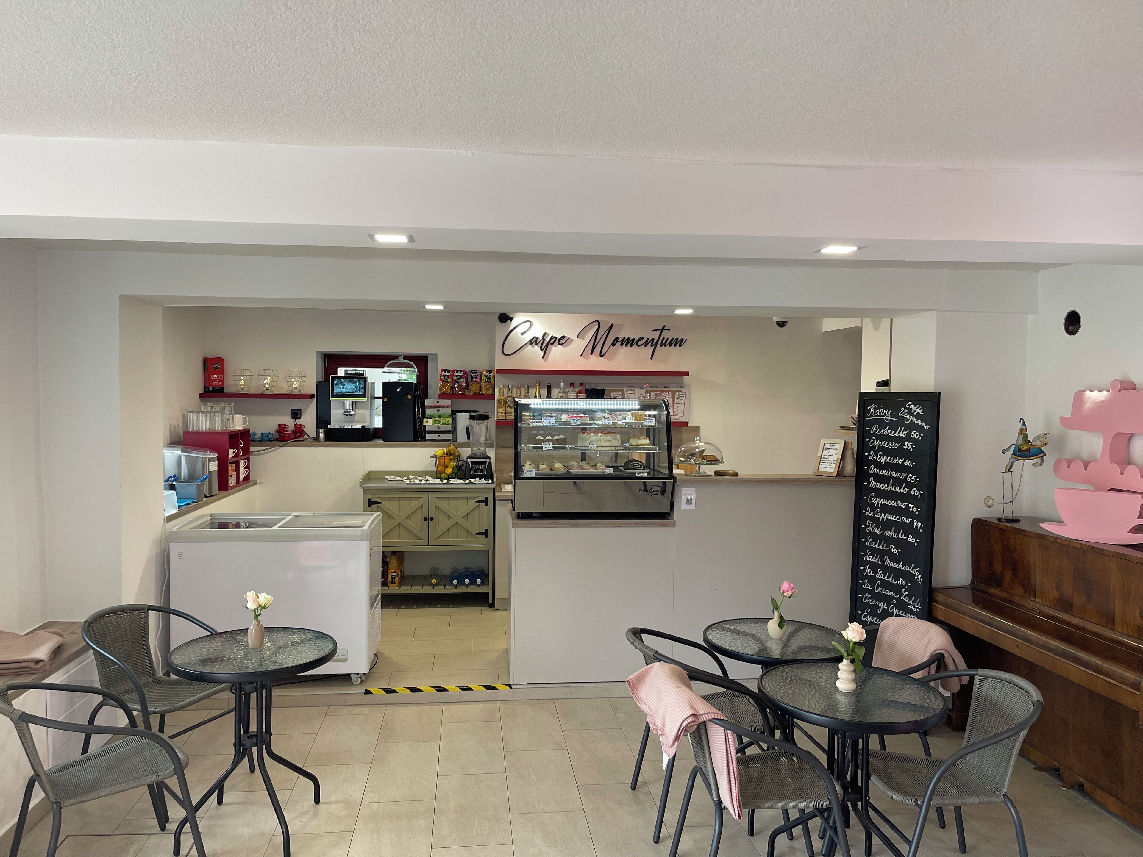 A cafe with a counter, menu board, and seating area with tables and chairs.
