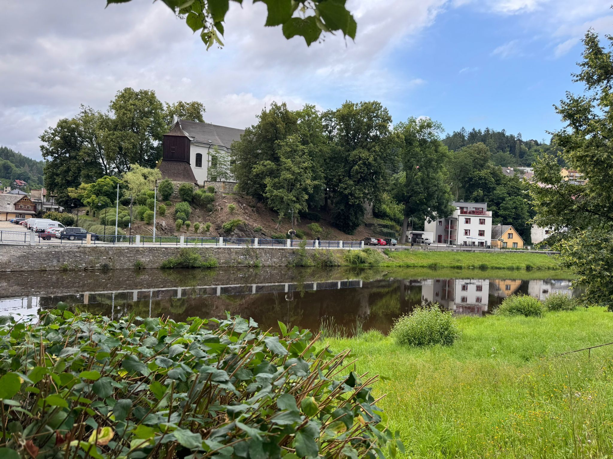 Aussicht auf einen Fluss mit einer Brücke, einem Gebäude mit Satteldach und einem Spiegelbild im Wasser.