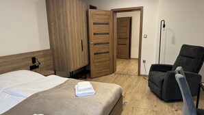 Une chambre d’hôtel comprenant un lit, une chaise, une armoire et une porte donnant sur une autre pièce.