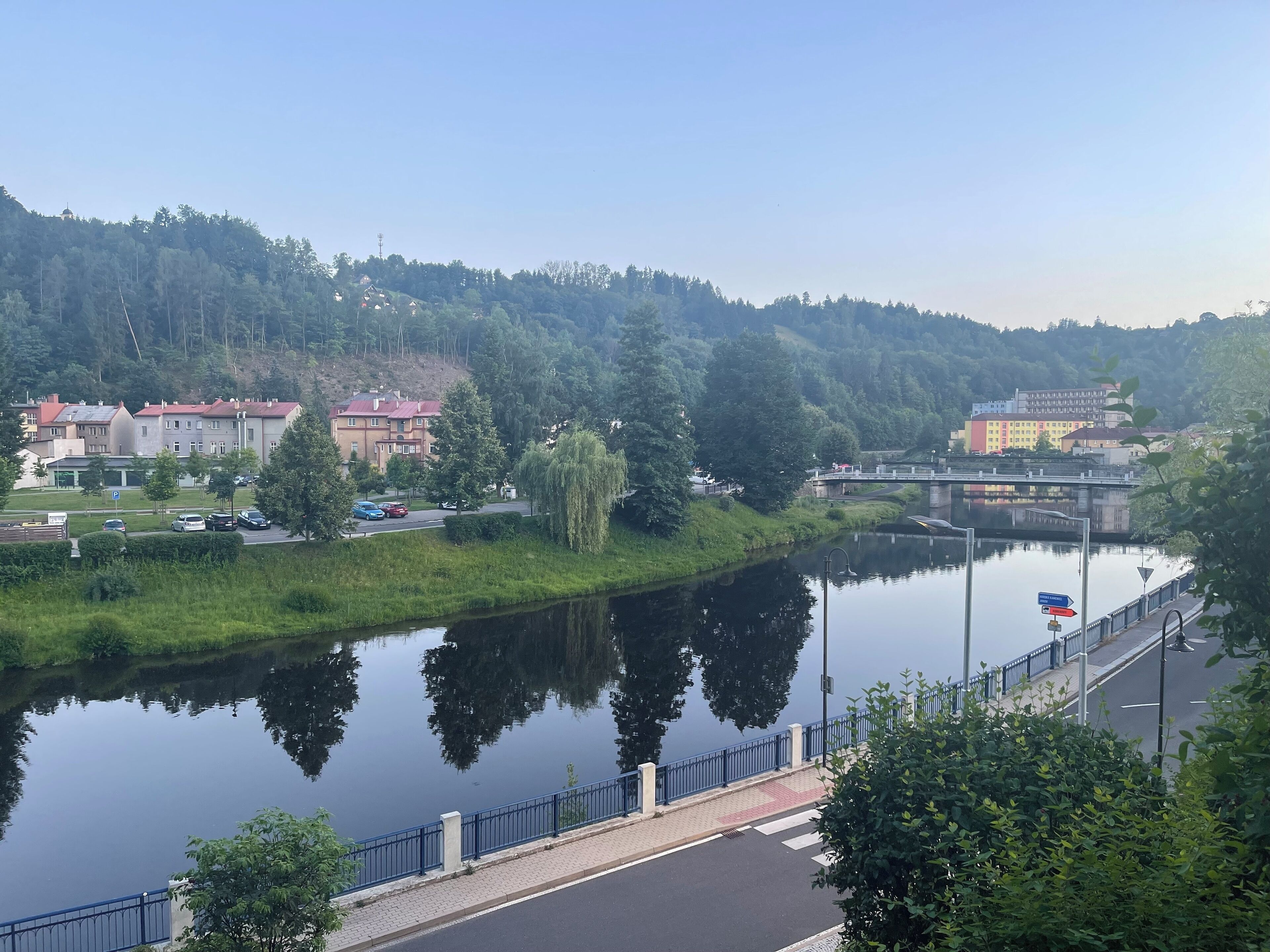 A riverside view with a bridge, buildings, and greenery.
