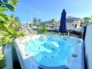 A hot tub with a clear view of the surrounding area, including a dock, boats, and nearby buildings. - Relaxed Coastal Living: 4BR Key Largo Home w/ Boat Lift & Island Charm (Key Largo)