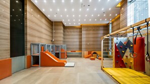 A modern indoor play area with a slide, climbing wall, and gym equipment. - Stylish 1BR Apartment at Meera Tower (Dubai)