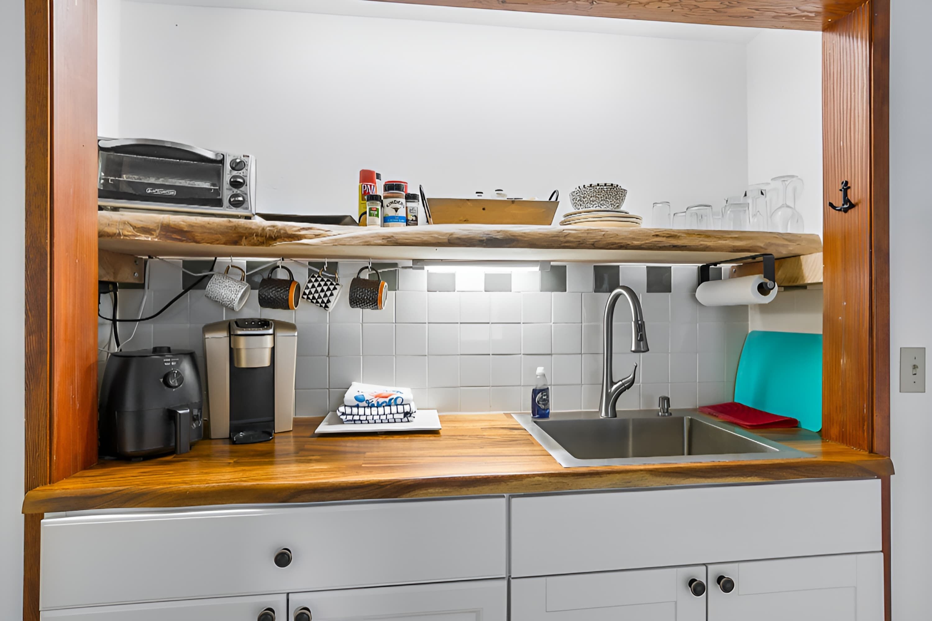 A compact kitchen with a wooden countertop, a built-in oven, a coffee maker, and a sink.
