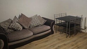 Un soggiorno con divano, cuscini decorati, un tavolo da pranzo e una lampada a sospensione.