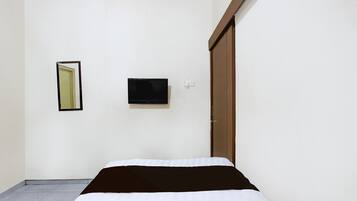 A room with a bed, a television mounted on the wall, and a door.