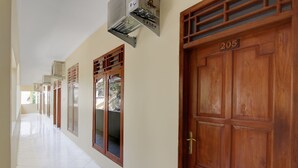 A corridor with wooden doors, each marked with a number, and a ceiling-mounted air conditioning unit. - Hotel O Homestay Ka Villa Syariah (Ngrombo)
