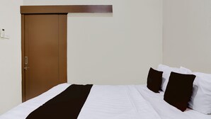A hotel room with a single bed, a brown door, and a white wall. - Hotel O Homestay Ka Villa Syariah (Ngrombo)
