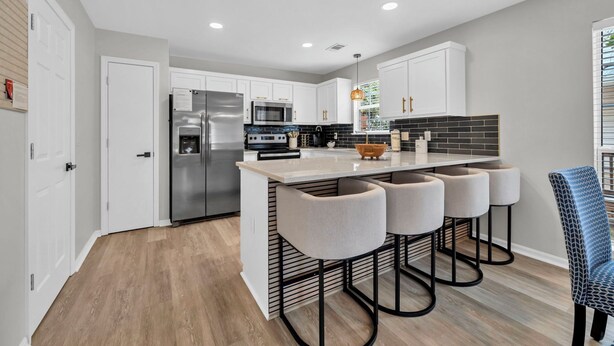 A modern kitchen with white cabinets, stainless steel appliances, and a central island with bar stools. - ☀️Beautiful Views-Bikes-Pet Friendly-30A-Milo's Beach Bungalow☀️ (Santa Rosa Beach)
