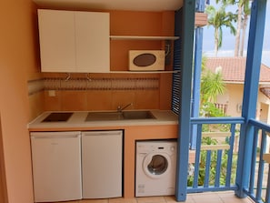 Une petite cuisine équipée comprenant un lave-linge, un petit réfrigérateur et un four à micro-ondes.