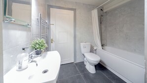 A modern bathroom with a white sink, toilet, and bathtub.