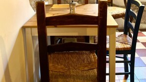 A stone wall, wooden table, and chairs in a dining area. - Antico Sogno (Bosa)