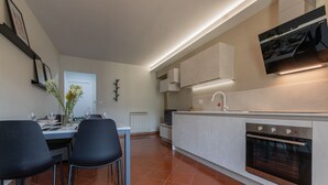 Una cocina moderna con horno empotrado, un comedor con dos sillas y una encimera blanca.