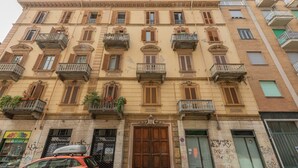 Un edificio de varios pisos con balcones, una puerta de madera grande y un escaparate con letreros.