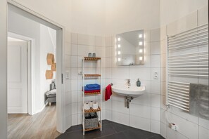 Une salle de bain moderne avec un lavabo blanc, un miroir et des murs carrelés.