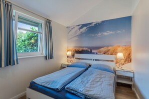 Une chambre à coucher avec un lit, deux tables de chevet, une fenêtre avec des rideaux et une grande fresque murale.