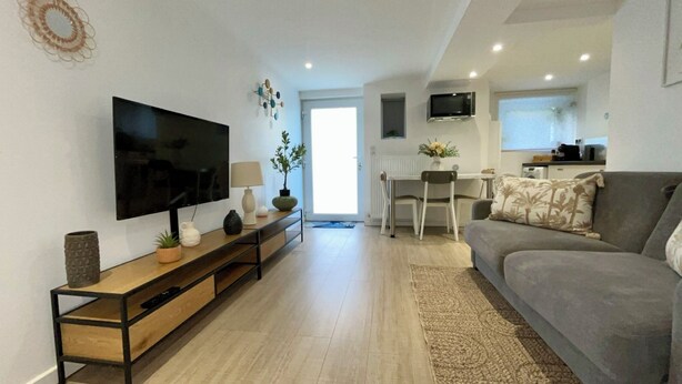 A modern living room with a flat-screen TV, wooden entertainment unit, and a grey sofa. - New / Oasis in the Heart of Nancy with Garden and Free Parking 🍃 (Nancy)