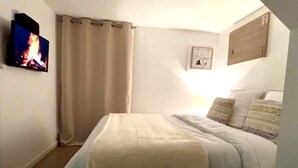 A bedroom with a bed, a TV mounted on the wall, and a curtain. - New / Oasis in the Heart of Nancy with Garden and Free Parking 🍃 (Nancy)