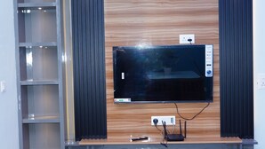 Un meuble de divertissement moderne doté d’un téléviseur à écran plat, d’étagères int égrées et d’une finition en bois.