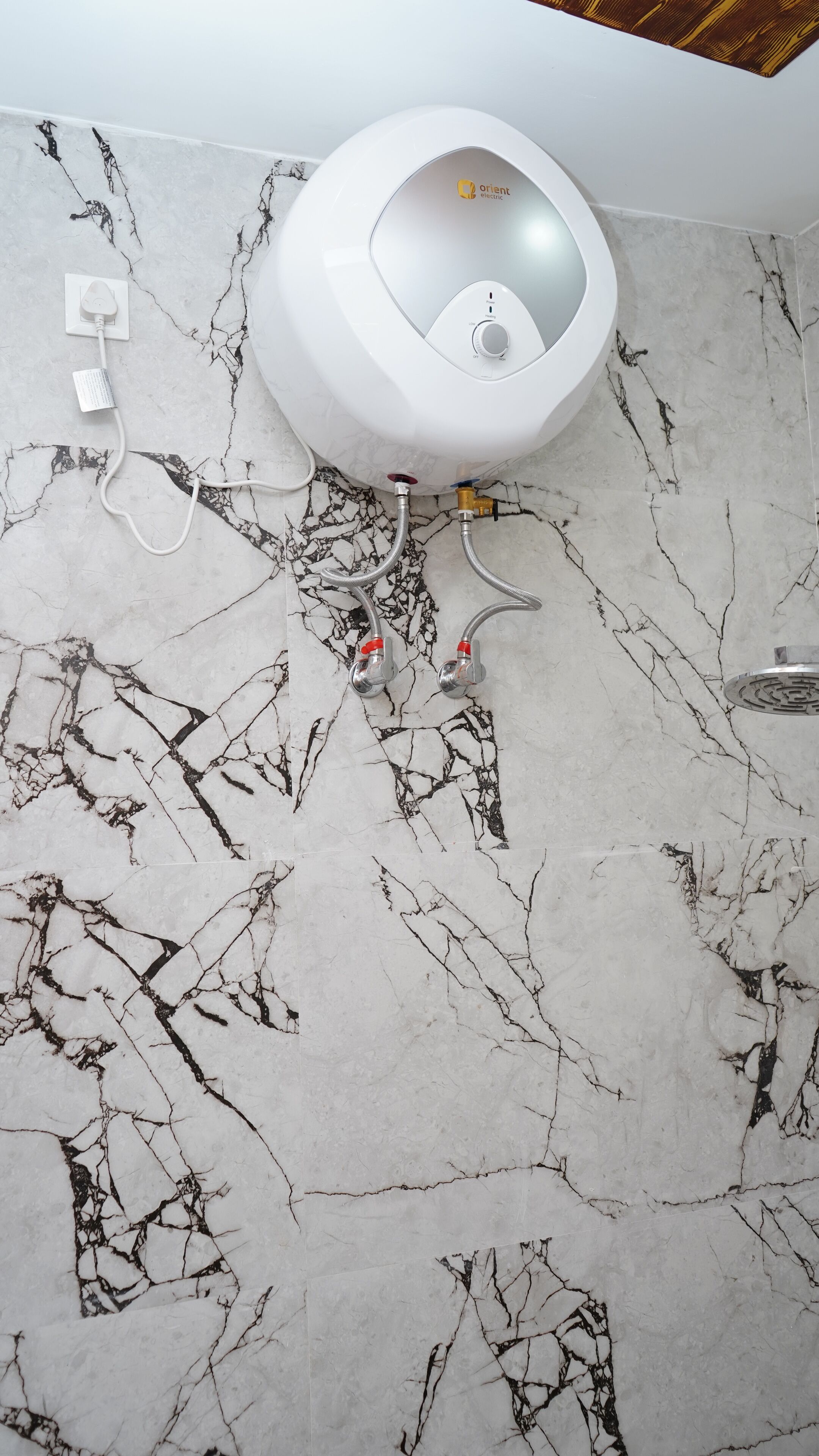 A bathroom with a white toilet, marble-patterned walls, and visible plumbing.