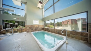 A spa with a large indoor pool, a sauna, and a view of the surrounding buildings.