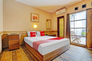 A hotel room with a wooden bed, a nightstand, a mirror, and a sliding glass door to a balcony. - Hotel O Guest House Cigadung 9a (Bandung)