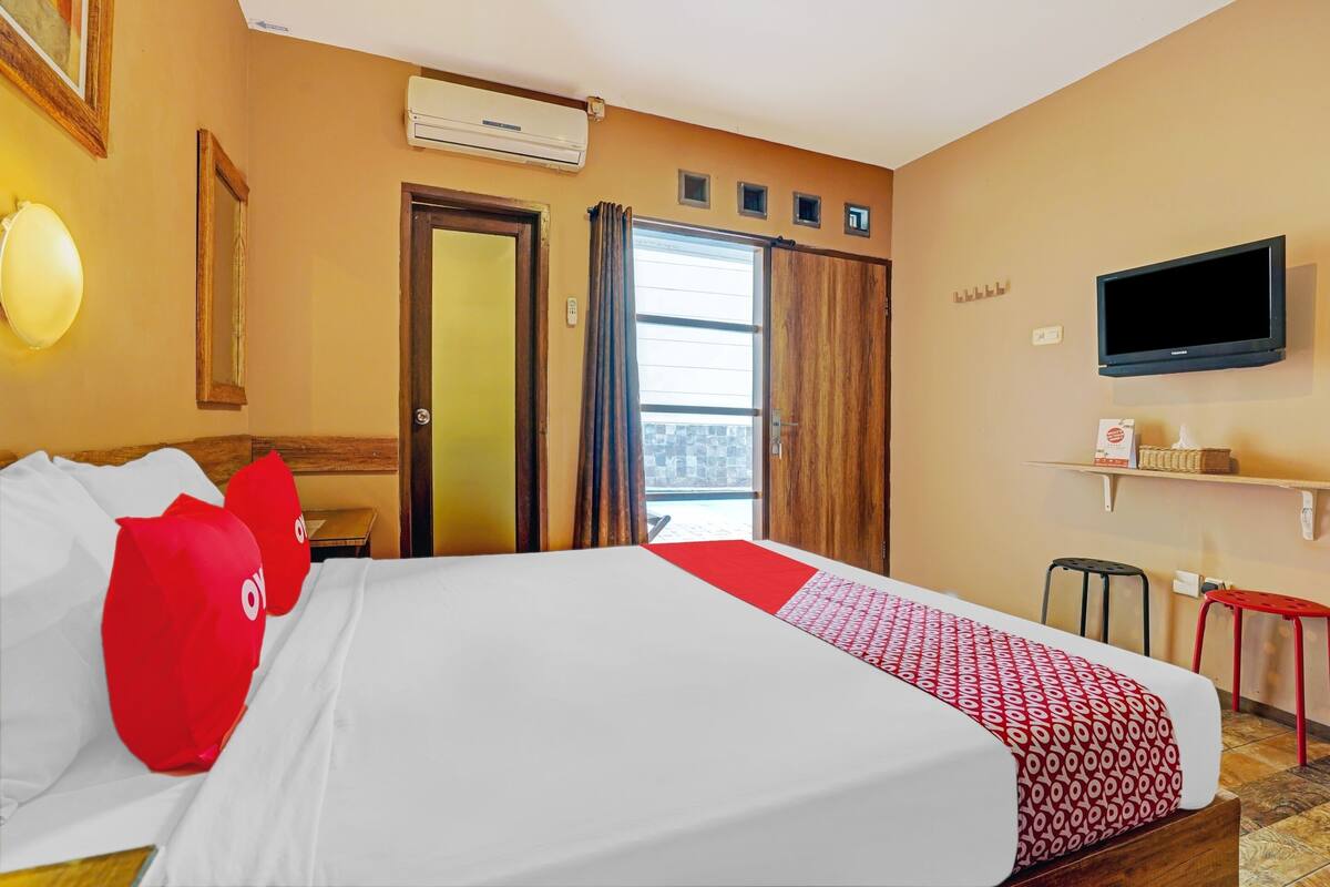 Une chambre d’hôtel avec un lit, une télévision, une fenêtre et une porte.