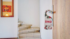 A staircase leading to a room with a wooden door and a wall-mounted sign with the letters "DND". - Hotel O Guest House Cigadung 9a (Bandung)
