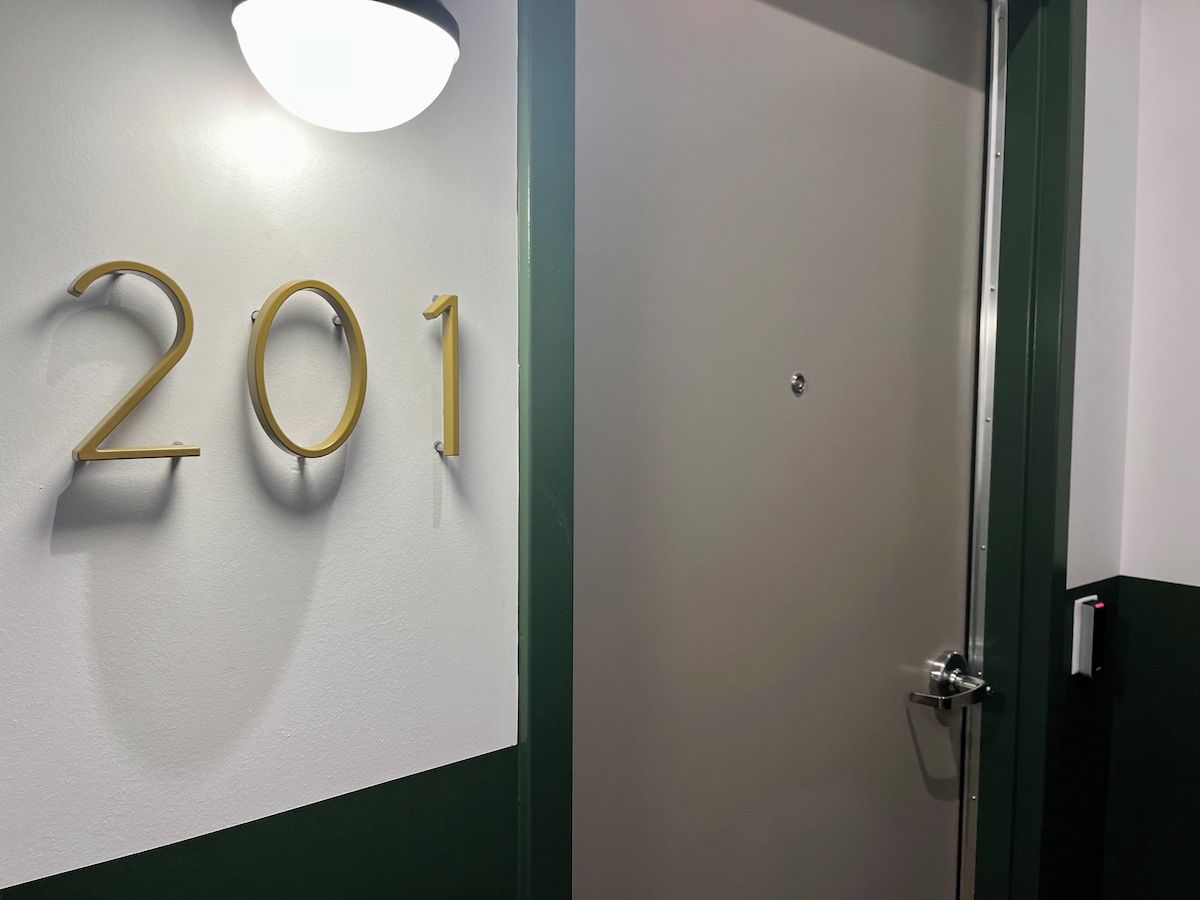 A wall with the number '201' indicating a room number, a door with a handle, and a light fixture above the door.