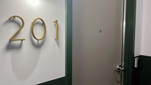 A wall with the number 201, a door, and a light fixture. - Stylish 2-Bed Downtown Loft (Toledo)
