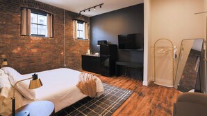 A bedroom with a bed, a desk, a TV, and a shower. - Downtown Loft at 5/3 Field! (Toledo)