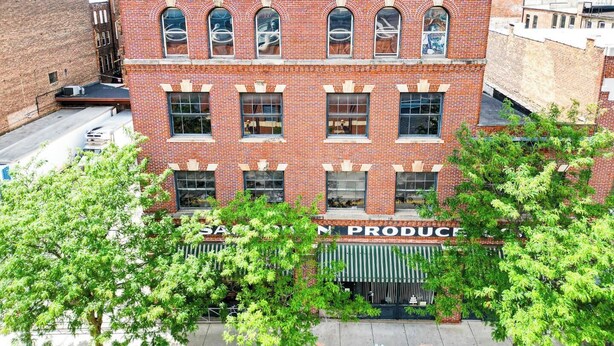 A red brick building with multiple windows and a storefront labeled "SAC PRODUCE". - Downtown Loft at 5/3 Field! (Toledo)