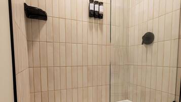 A bathroom with a shower, toilet, and a towel rack.