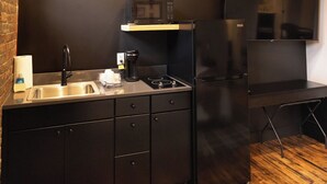 A modern kitchen with a black countertop, stainless steel sink, and black cabinets. There is a microwave, a stove, and a refrigerator. - Downtown Loft at 5/3 Field! (Toledo)