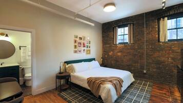 A bedroom with a bed, a nightstand, a chair, a dresser, a mirror, and a window.