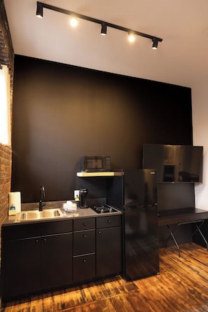 Una cocina moderna con encimera negra, pileta de acero inoxidable y microondas integrado.