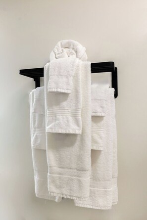 A white towel folded and hanging on a black towel rack. - Toledo King Loft | Ballpark & Dining | Suite 203 (Toledo)