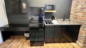 A compact kitchen with a refrigerator, microwave, sink, and a small countertop.