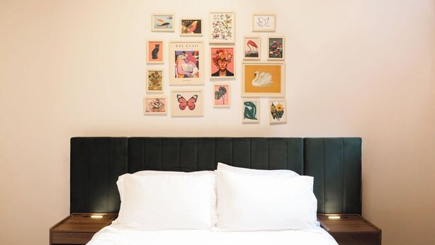 A neatly made bed with white linens and a dark headboard in a hotel room. - Toledo Loft | Walk to Ballpark | Suite 204 (Toledo)